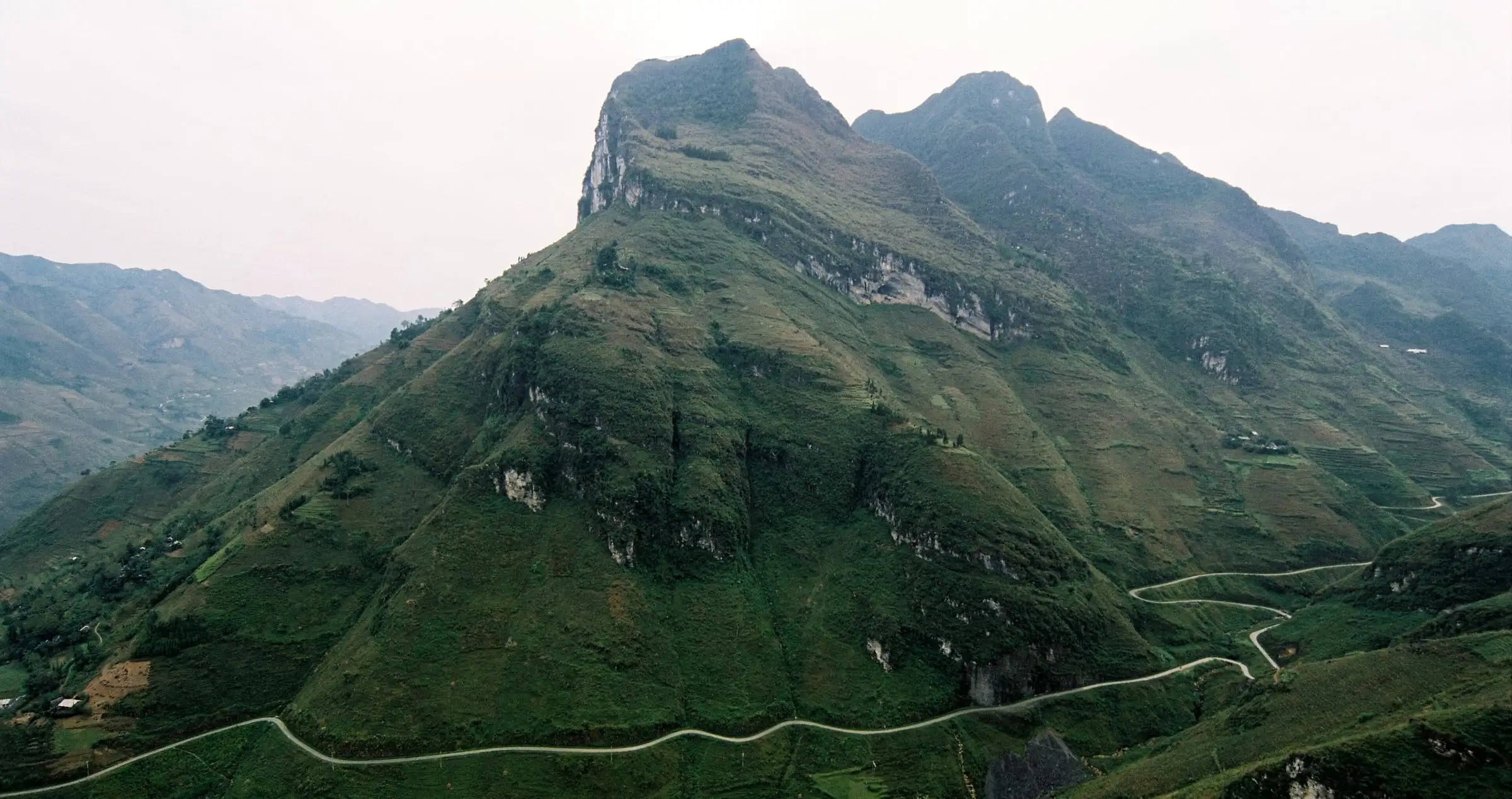 A road winding beneath the limestone peaks of Mã Pí Lèng Pass in Ha Giang, northern Vietnam